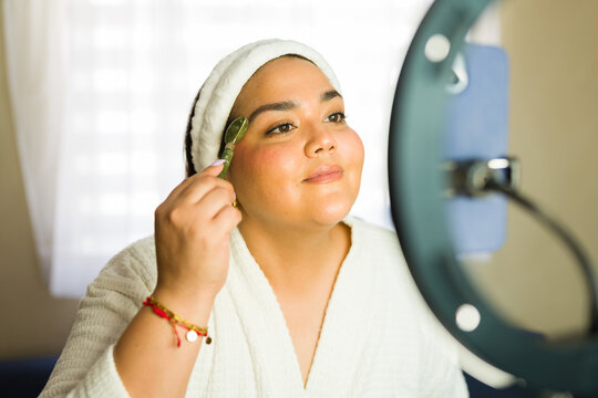 Woman recording skincare routine with jade roller for her followers