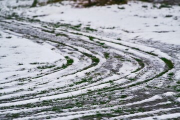 Tire tracks in melting snow on grass