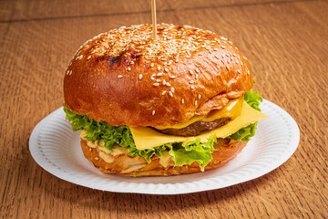 A delicious cheeseburger sits on a plate, featuring layers of cheese, lettuce, and a juicy patty