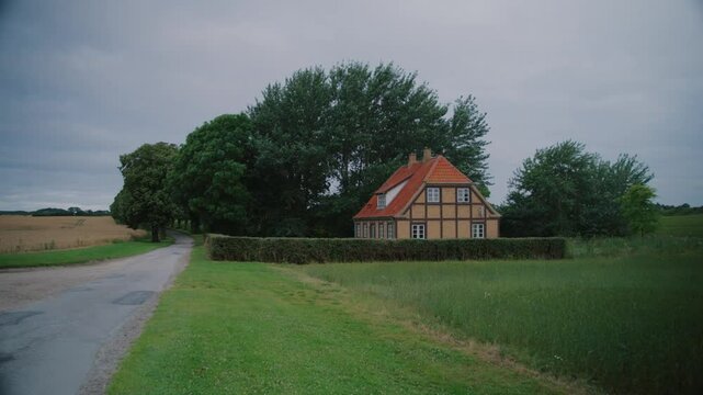 House on a rural road in Langeland, Denmark, surrounded by lush green trees and fields