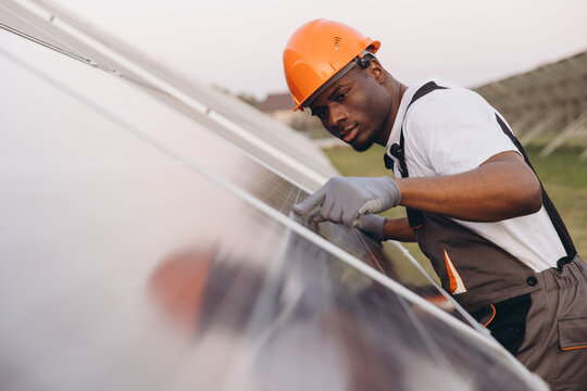 African American Male Engineer Inspecting Solar Panels For Renewable Energy Solutions - Powered by Adobe