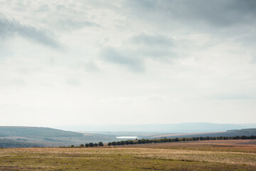 Autumn landscape in the countryside. Cloudy sky above a valley in north-east of Moldova. Agricultural land lined with trees.