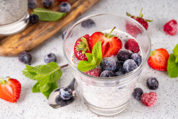 Chia seeds pudding with fresh berries. Healthy summer breakfast dessert with creamy milk or yogurt, chia, strawberry and blueberry, white table background copy space