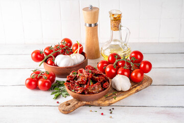 Homemade sun-dried tomatoes in olive oil, gourmet italian food ingredient, with fresh tomatoes, oil bottle and spices on kitchen table