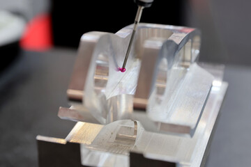 Computerized measurement and control device of the dimensions of a metal engine block part with a probe stylus ball tip of multi-axis coordinate measuring machine.