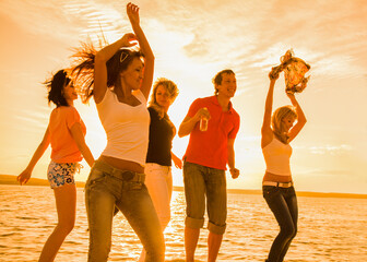  group of young people happily dancing on the seashore at sunset