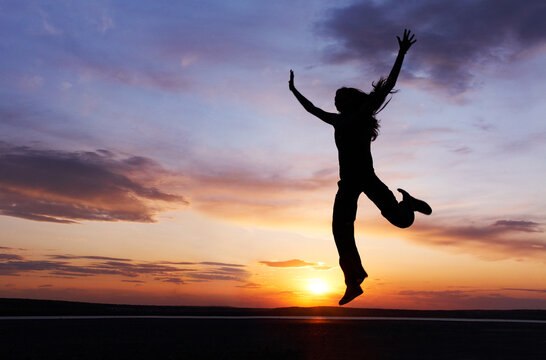 One young girl enjoys her vacation at sunset. Silhouette.
