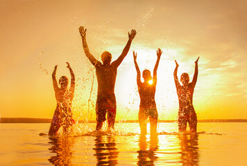 Group of young people enjoying their vacation at sea at sunset. Silhouettes.