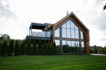 Modern wooden house with glass facade and spacious grassy surroundings