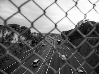 フェンスと高速道路。モノクロ。