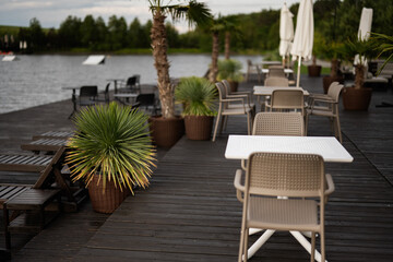 Outdoor café seating area by a lake with scenic tropical plants and views