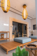 Modern spa area in a boutique hotel featuring a glass enclosed sauna, light wood furniture, pendant lights, and serene decorative elements.