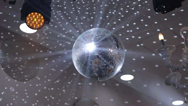 Disco ball rotating nightclub radiating glitter rays closeup.