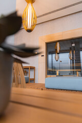 Luxurious interior featuring a wooden pendant light, glass enclosed sauna, wooden table with blue cushioned chairs, and contemporary design elements.