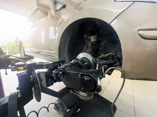 Car suspension and brake system under diagnostic machine during auto service repair. Automotive maintenance with mechanical tools in workshop.