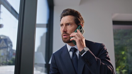 Worried ceo talking mobile phone sitting cozy cafeteria table alone zoom out