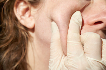 Close-up of female's cheek during skincare routine with gloved hand pressing skin.
