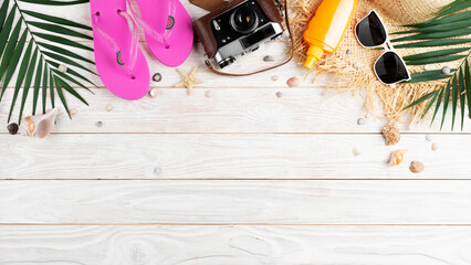 Vacation travel planning background of film camera, straw hat, sunglasses, palm leaves, flip flops and shells on white planks