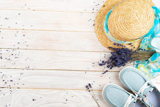 Straw hat, lavender flovers and  fabric moccasins on white planks vacation planning background flat lay with copy-space