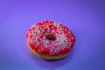 Flat lay of pink donut decorated with sprinkles on blue background
