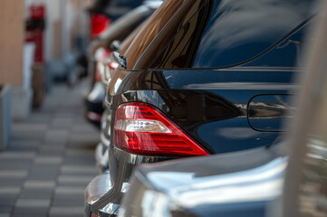 Luxury cars lined up in a parking lot on a sunny day in an urban setting