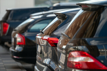 Rows of black vehicles parked in a sunny urban setting during late afternoon hours