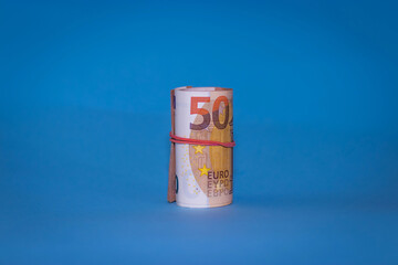 50 euro bank notes rolled and wrapped together.About 2500 worth. on blue background