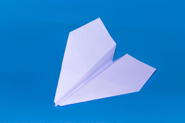 Flat lay of white paper plane and blank paper on pastel blue color background.