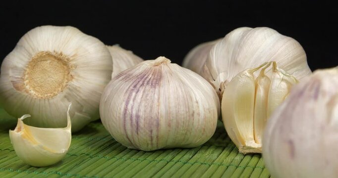 Garlic rotates on black background. Garlic, Allium sativum, species of bulbous flowering plants in genus Allium. Garlic - very healthy product with many beneficial properties for health