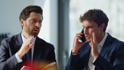 Frustrated startupers talking smartphone having problem at light cabinet closeup