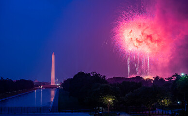 Pink fireworks in Washington, D.C. with the Washington Monument and Reflecting Pool in the background at night.
