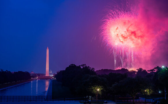 Pink fireworks in Washington, D.C. with the Washington Monument and Reflecting Pool in the background at night. - Powered by Adobe
