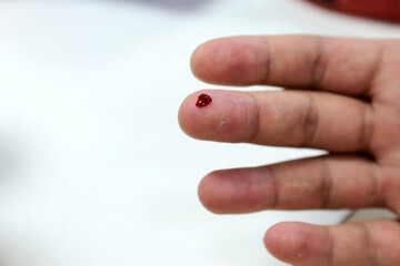 A person's finger is pricked by a doctor to collect a drop of blood for a medical test.
