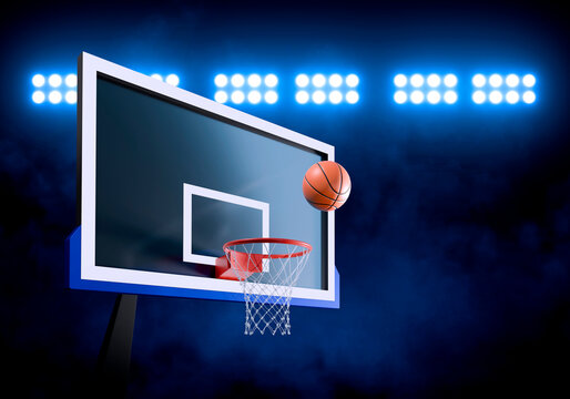 Orange basketball floating above the hoop net. in a stadium filled with spotlights