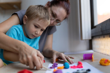 Fototapeta premium Teacher helping child playing with clay in art class