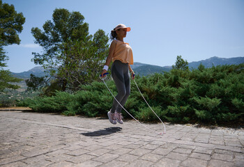 Woman Enjoying Outdoor Fitness Jump Roping in a Serene Mountain Landscape