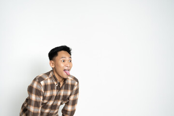A cheerful young man in casual clothing expressing himself playfully while sticking out his tongue, radiating fun energy.
