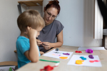 Fototapeta premium Teacher helping child with modeling clay in art class