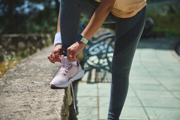 Woman Tying Running Shoe Laces Outdoors Before Exercising