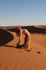 Woman doing yoga pose in the desert dunes