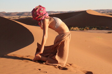 Woman doing yoga pose in the desert dunes