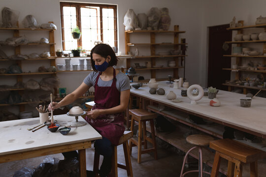 Pottery wheel rotating at wooden table with ceramic bowl receiving glaze near sunlit window