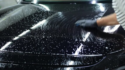 Worker clean car body with blue clay for cleaning before applying protective layer or coating to auto