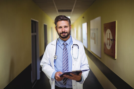 Hospital corridor featuring yellow walls and patient room doors under fluorescent ceiling lights