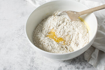 mixing flour into vanilla cookie dough in a white mixing bowl, plain vanilla cookie dough about to...