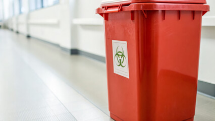 Biohazard waste medical concept shown by red container in hospital hallway for safety awareness