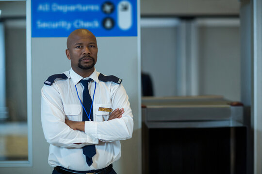 African American security officer standing with arms crossed at airport checkpoint showing badge