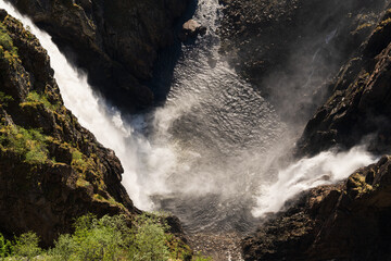 A powerful double waterfall plunges into a rocky canyon in Norway. A majestic view of the churning water streams and untouched Scandinavian nature.