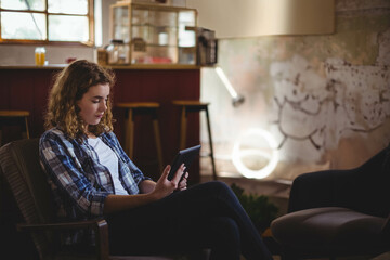 Female sitting in armchair holding tablet near coffee shop stools pastry display neon ring light