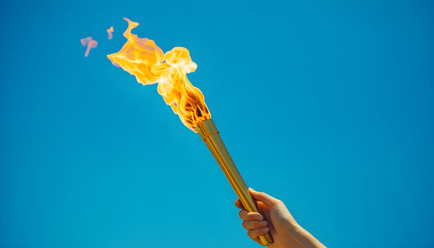 Hand holding Olympic flame against blue sky. Symbol of international sports games. Gold torch with burning flame, victory achievement concept. Success sports games